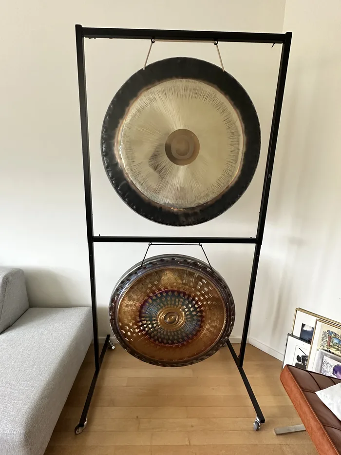 Two gongs on a black stand: a silver-brushed gong above a hammered bronze gong with a blue spiral centre